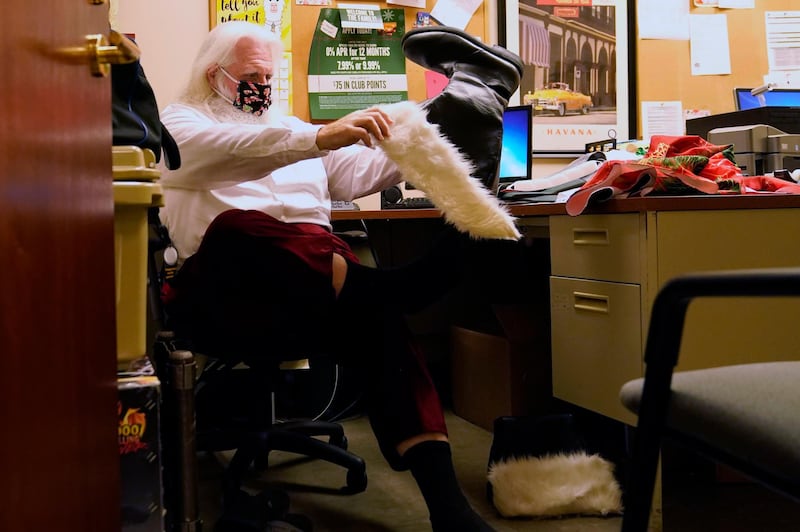 Brad Six wears a protective face mask as he puts on his boots preparing to work as Santa Claus in Miami. AP Photo