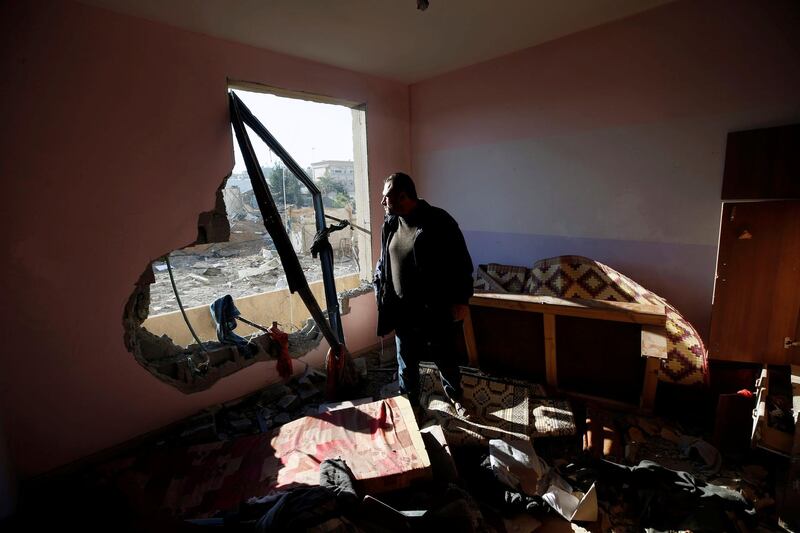 A Palestinian man looks out of his apartment that was damaged in an Israeli airstrike at a nearby militant target. Mohammed Salem / Reuters.