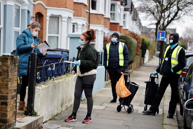 Volunteers collect completed coronavirus tests from a local resident in West Ealing. AFP
