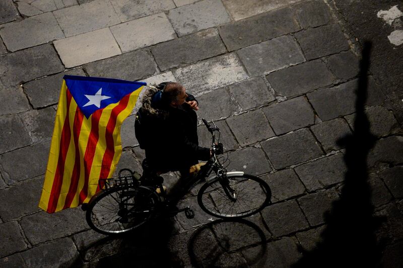 A man rides a bicycle holding a Catalan pro-independence 'Estelada' flag after a demonstration called by employees of the Generalitat (Government of Catalonia) at the Sant Jaume square in Barcelona on November 21, 2017 in protest against the Article 155 of the Spanish constitution, which Madrid has used to impose direct rule over the semi-autonomous Catalonia region,  / AFP PHOTO / Josep LAGO