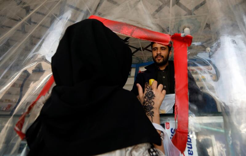 A Yemeni pharmacist serves a customer behind a plastic shield  in Sanaa. EPA
