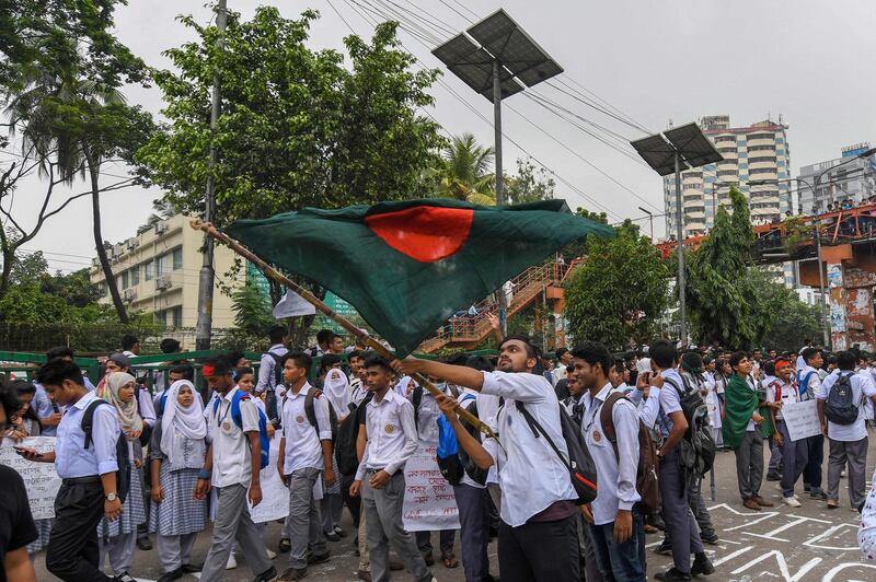 A Bangladeshi student wave Bangladesh's national flag as they block a road during a student protest in Dhaka.  AFP PHOTO / MUNIR UZ ZAMAN