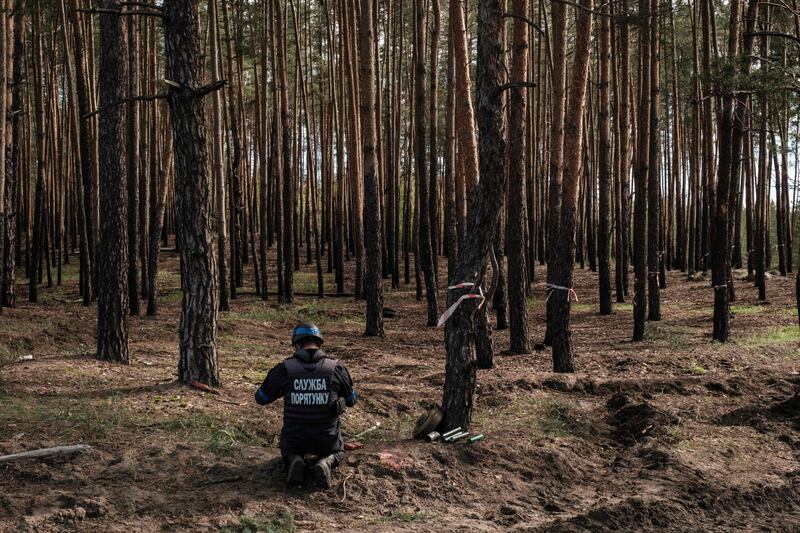An officer from a Ukrainian national police emergency demining team prepares to detonate collected anti-tank mines and explosives near Lyman, in the Donetsk region. AFP