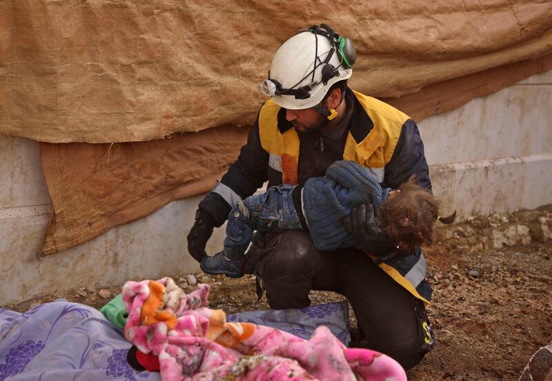 CORRECTION / EDITORS NOTE: Graphic content / A member of a Syrian civil defence team, known as the White Helmets, carries the body of one of several children, killed along with eight other adults and children in an air strike in the rebel-held northern Aleppo province, for burial in a collective grave in the village of Urum al-Kubra on February 3, 2020. The airsttrike is one of the deadliest rounds of bombardment since an ongoing government offensive against the area started last month.
 / AFP / AAREF WATAD
