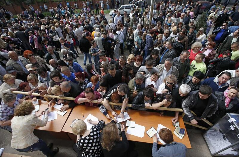 People stand in a line to receive ballots from members (behind desks) of a local election commission during the referendum on the status of Donetsk region in the eastern Ukrainian city of Mariupol May 11, 2014. East Ukrainian rebels pressed ahead with a referendum on self-rule on Sunday amid fears of civil war and pitched relations between Russia and the West into their worst crisis since the Cold War. Reuters