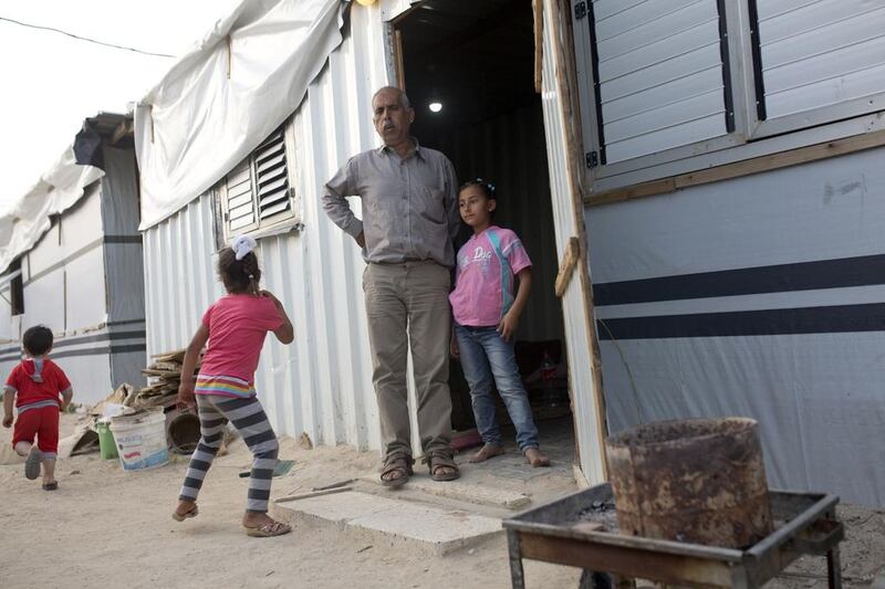 Mohammed Najjar, 48, stands with his family outside the caravan he is living in at the encampment in Khuza'a in the Gaza Strip on April 20, 2015. Heidi Levine for The National