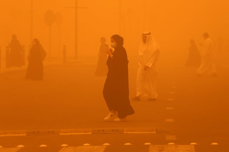 Pedestrians cross a road amid a severe dust storm in Kuwait City. AFP
