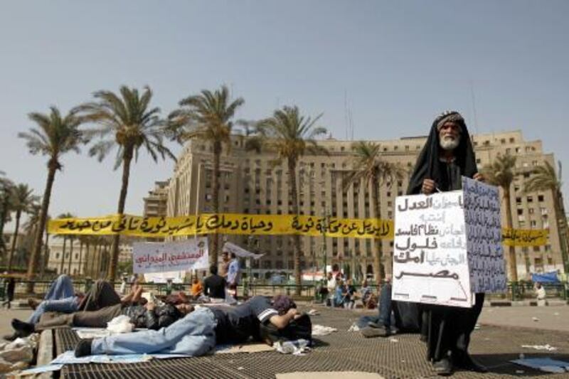 An elderly Egyptian protester holds a sign calling for justice for the sake of Egypt as other demonstrators sleep in Cairo's landmark Tahrir Square on June 3, 2012. Hundreds of demonstrators are occupying Tahrir Square after a court sentenced ousted president Hosni Mubarak and his interior minister Habib al-Adly to life in prison but acquitted six security chiefs in the deaths of protesters last year. AFP PHOTO/MOHAMMED ABED
 *** Local Caption ***  671799-01-08.jpg