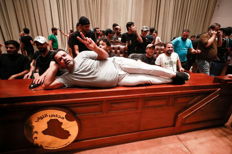 A demonstrator lies on the desk of the Speaker of the Iraqi parliament. AFP