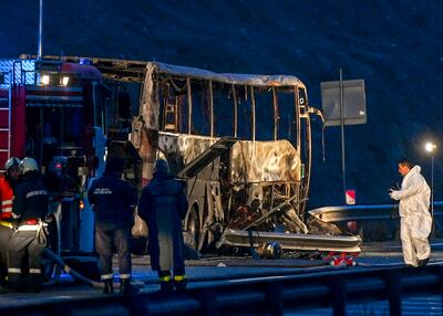 Fire fighters, police officers and investigators inspect the charred wreckage of a bus after at least 46 people including 12 children died in a fire. The bus crashed near the village of Bosnek in western Bulgaria at around 2am on Tuesday. Photo: EPA / VASSIL DONEV
   