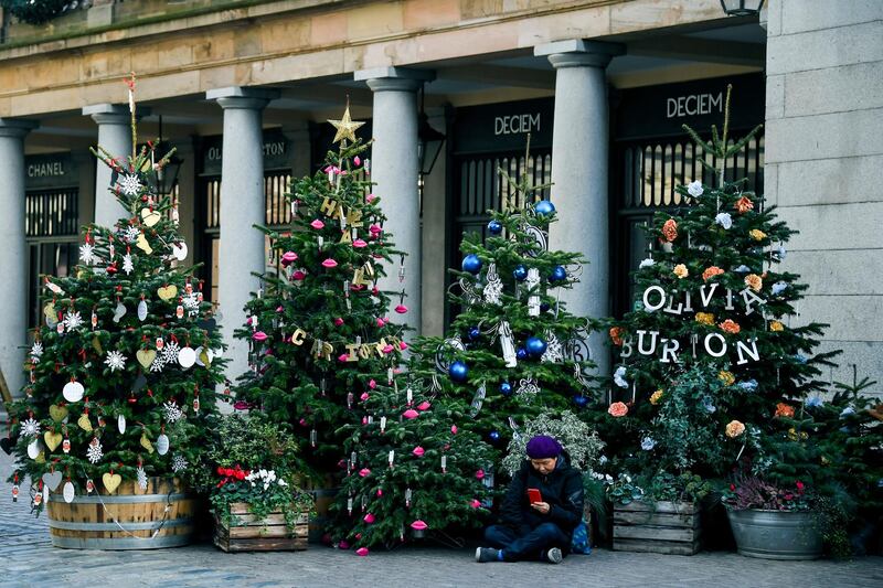 A woman sits amid Christmas trees in Covent Garden, in London. AP Photo