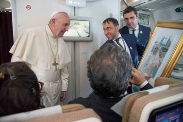 Pope Francis receives a gift from a journalist during his flight from Abu Dhabi to Rome. AP Photo