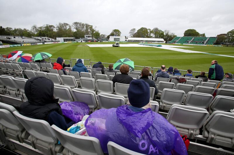 People wait in their seats as groundsmen work on the wet pitch at Malahide. Paul Faith / AFP