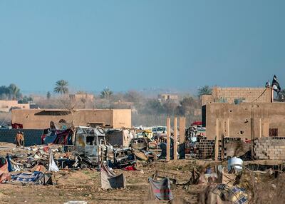 Men, suspected of being members of the Islamic State, walk next to a makeshift camp for Islamic State members and their families in the town of Baghouz, in the eastern Syrian province of Deir Ezzor, on March 9, 2019. More than 7000 people, mostly women and children, have fled the shrinking pocket over the past days, as US-backed forces press ahead with an offensive to crush holdout jihadists. / AFP / BULENT KILIC
