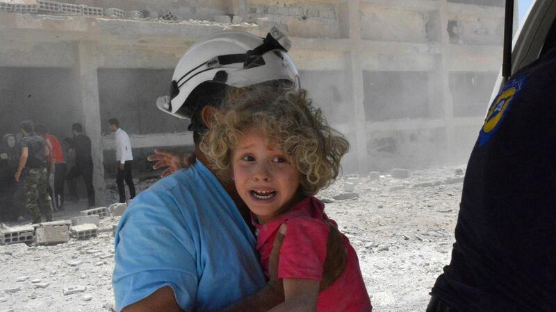 A Syrian Civil Defence member carries a child after air strikes hit a school in Deraa province. Syrian Civil Defence White Helmets via AP