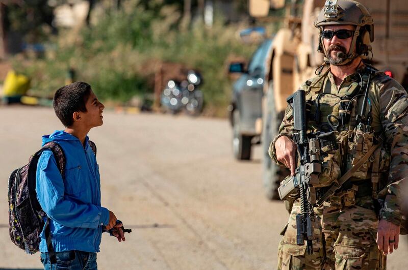 A Syrian boy looks at a US soldier on patrol in the village of Ein Diwar in Syria's northeastern Hasakeh province.  AFP