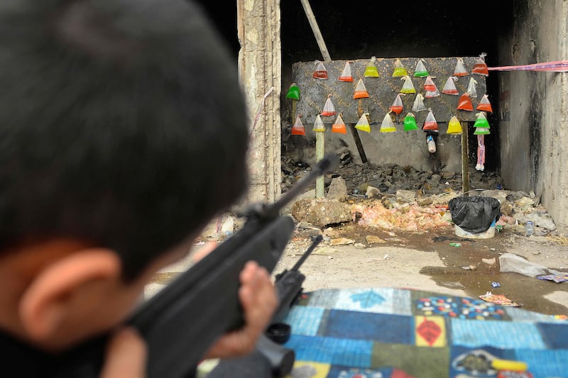 A child fires an air rifle at plastic targets filled with coloured liquid at a fairground during Eid Al Fitr in the northern Iraqi city of Mosul. AFP