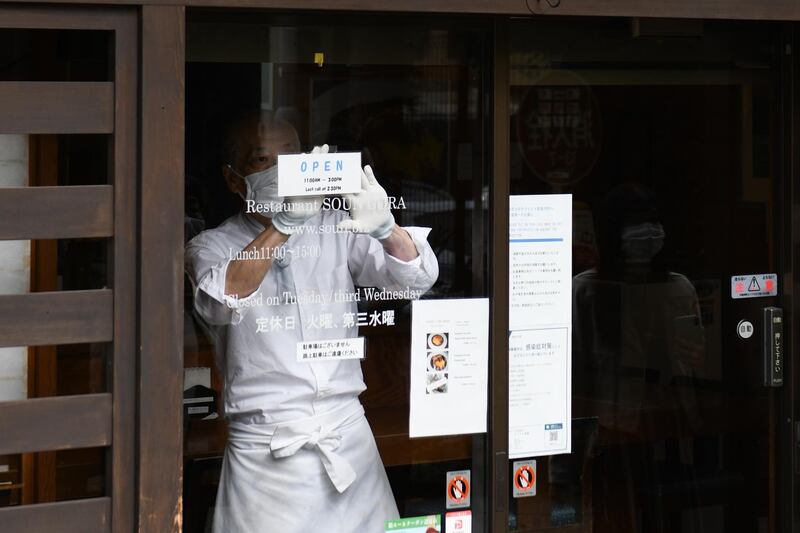 A staff member puts an 'open' sign on a restaurant door near Gora station in Hakone, Kanagawa Prefecture, Japan. A national Go To campaign aimed at spurring domestic travel added Tokyo starting this month. Rolled out in July, the campaign provides subsidies of up to 50% on transport, hotels and tourist attractions within Japan. Bloomberg