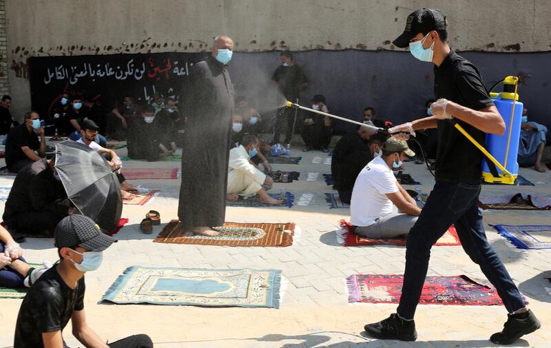 A medical personnel sprays disinfectant as Iraqi Shiite worshipers perform their Friday Prayers in Sadr City. EPA