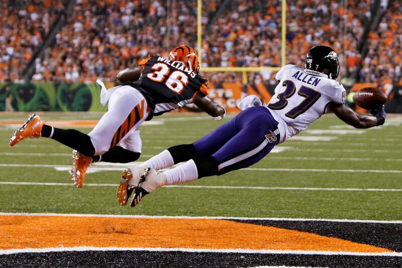 Baltimore Ravens running back Javorius Allen, right, tries to catch a pass while under pressure from Cincinnati Bengals defensive back Shawn William in the second half of an NFL football game in Cincinnati. Frank Victores / AP Photo
