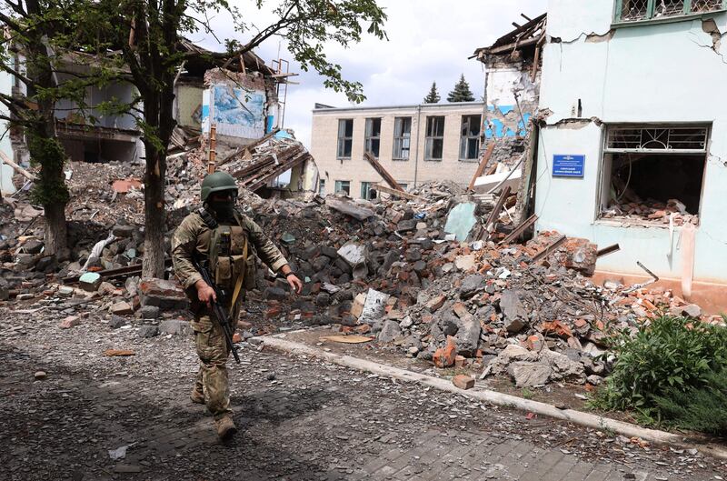 A Ukrainian serviceman passes by destroyed buildings in Siversk. AFP
