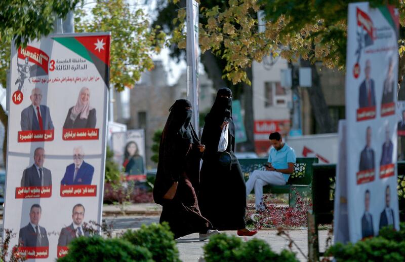 Women walk in a park filled with campaign posters and slogans of candidates for the upcoming Jordanian parliamentary elections line a street in the capital Amman. AFP
