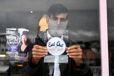 Rishi Sunak, chancellor at the time, places an 'Eat Out to Help Out' sticker in the window of a business. PA