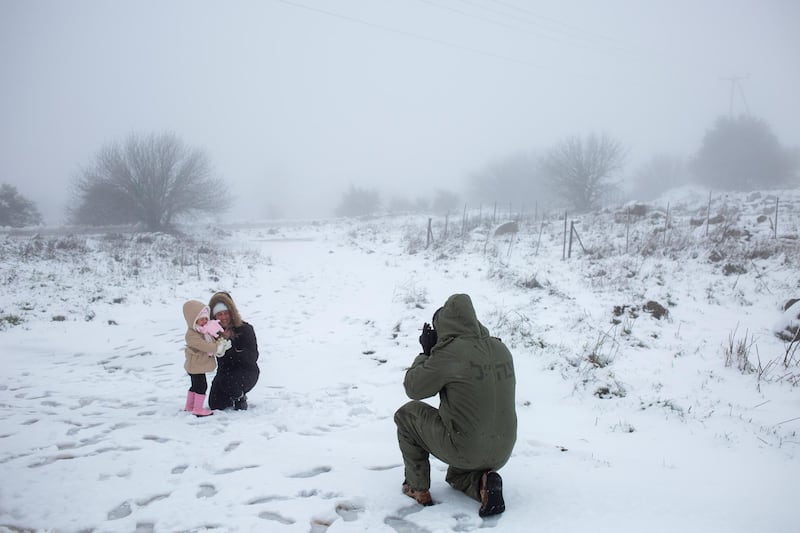 A man photographs his family in the snow near the Quneitra border crossing between Syria and the Israeli-controlled Golan Heights. AP