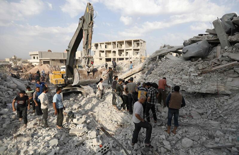 Syrians gather amidst destruction in Zardana, in the mostly rebel-held northern Syrian Idlib province, in the aftermath of following air strikes in the area late on June 8, 2018. Air strikes in northwestern Syria, thought to have been carried out by regime ally Russia, killed 28 civilians including four children, a Britain-based monitor said. The raids, which hit a residential zone in the area of Zardana in the northwestern province of Idlib, also wounded 50 people, the Syrian Observatory for Human Rights monitoring group said.
 / AFP / OMAR HAJ KADOUR
