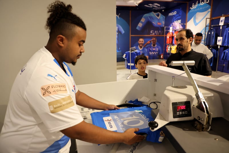 Fans wait as Neymar's name and number are printed on to an Al Hilal shirt in the club shop. Reuters