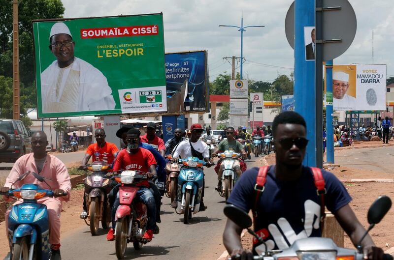 People ride their motorcycles past electoral bilibaords of Soumaila Cisse, leader of of URD (Union pour la Republique et la Democratiie), one of the main opposition party in Bamako, Mali July 23, 2018. REUTERS/Luc Gnago