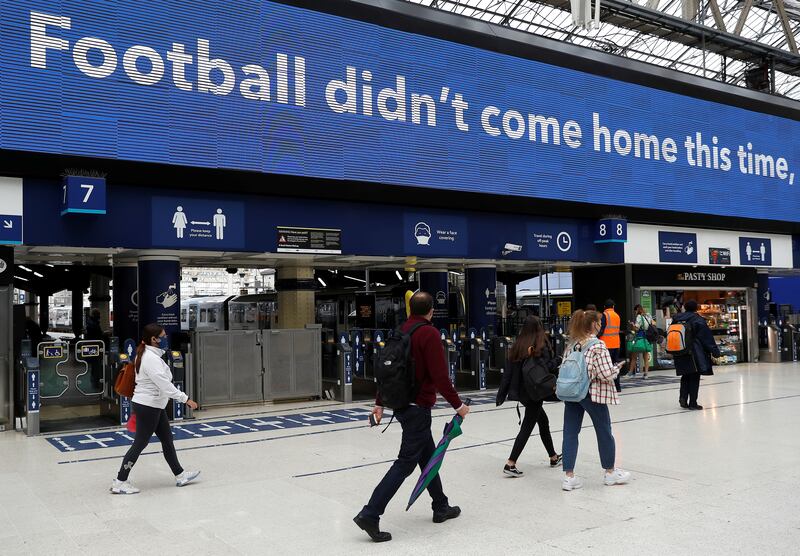 Commuters walk past an advertising board which refers to the Euro 2020 final result, in Waterloo station, London.