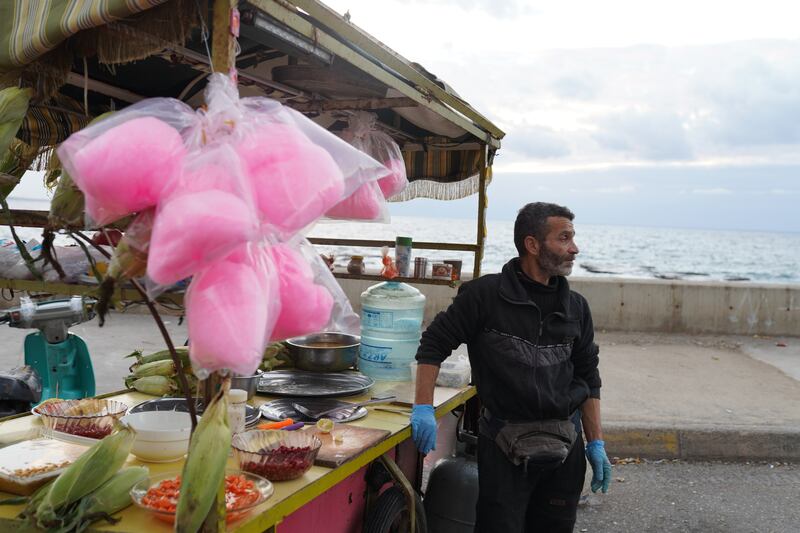 A Syrian refugee stands by his cart where he sells corn, beans, pomegranate and other snacks by the sea.