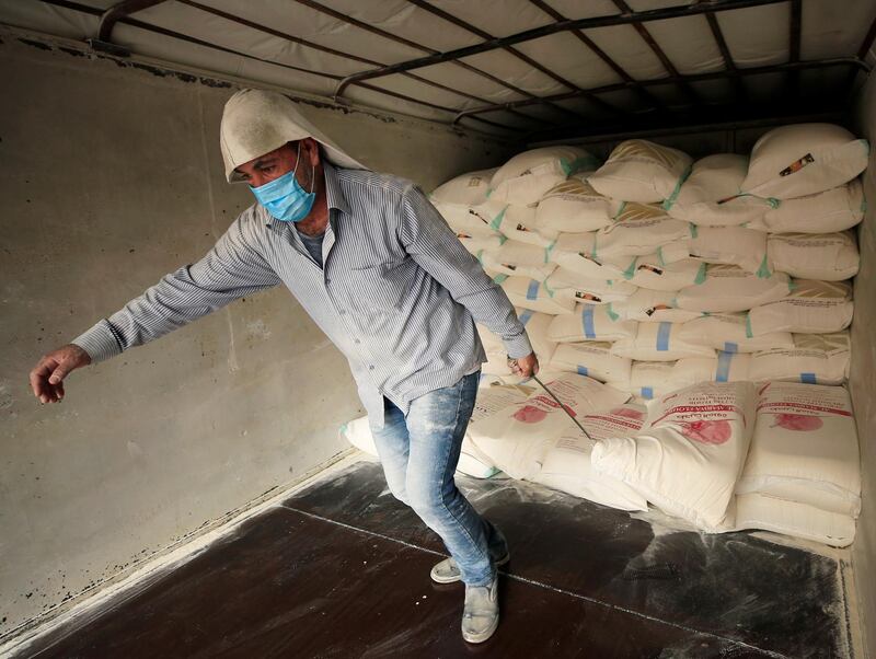 A worker wearing a protective mask unloads a sack of flour in Sidon, Lebanon. Reuters