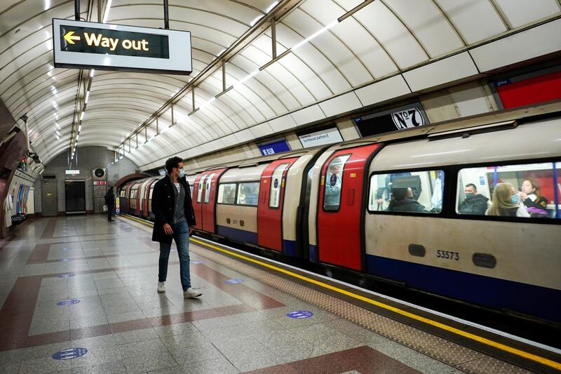 A passenger wearing a face mask walks along the platform as an underground train approaches, in London. AP Photo