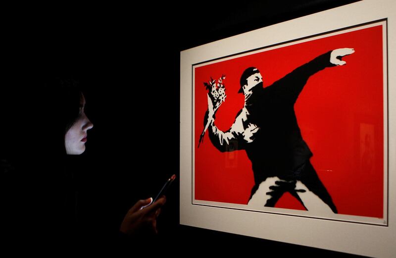 A woman looks at the artwork 'Love is in the Air, Flower Thrower', by British artist Banksy, as she visits the 'unauthorised' exhibition 'Banksy, genious or vandal?' during its opening in Madrid, Spain. EPA