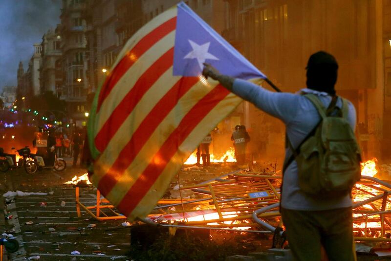 People wave 'Esteladas' flag, the unofficial flag typically flown by Catalan independence supporters, during incidents with police as thousands of people take part in one of the so-called 'Marches for Freedom' along Pelayo street in Barcelona, Spain.  EPA