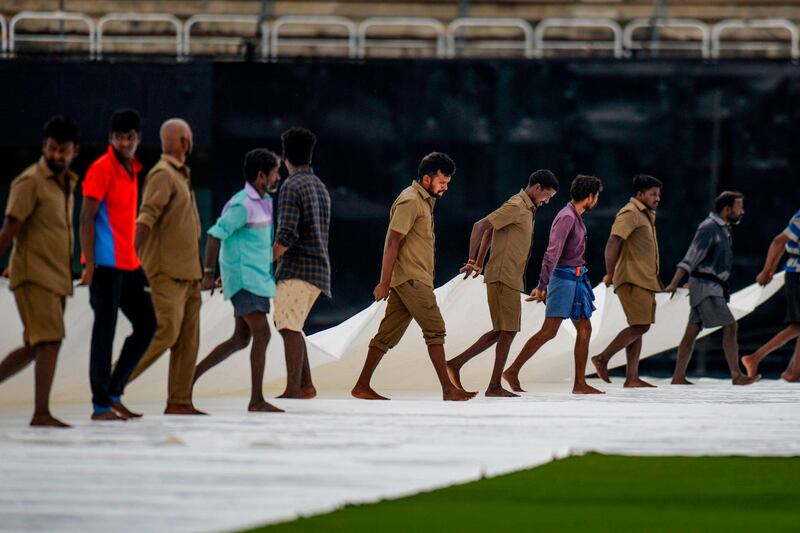 Ground staff cover the pitch after a drizzle at the MA Chidambaram Stadium in Chennai. AFP