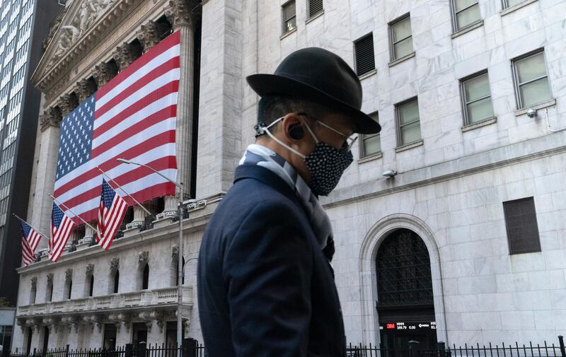 FILE - In this Nov. 16, 2020 file photo a man wearing a mask passes the New York Stock Exchange in New York. Stocks are opening moderately lower on Wall Street, edging below the record highs they set a day earlier. The S&P 500 fell 0.4% shortly after the opening bell Wednesday, Dec. 2. (AP Photo/Mark Lennihan, File)