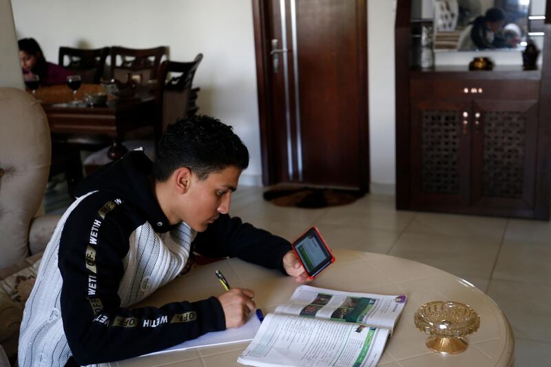 A Palestinian student follows through his mobile telephone from his home, a lesson broadcast by a teacher from an educational radio station, during his isolation period in a bid to prevent the spread of the novel coronavirus, in Gaza City.  AFP