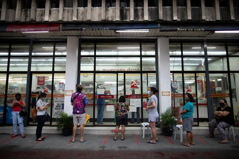 Filipinos queue outside a pharmacy at a public market in Manila. Reuters