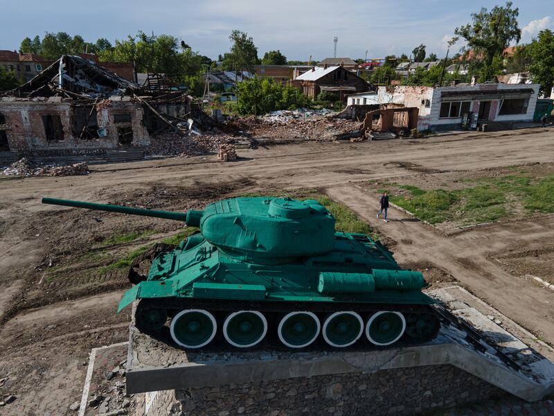 A young woman walks near a damaged Soviet tank monument in Trostyanets, Ukraine. Getty Images