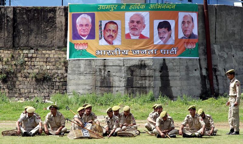Jammu and Kashmir police men take rest in front of election campaign banner of Bharatiya Janata Party (BJP) at Udhampur, 65 KM from Jammu, the winter capital of Kashmir. Jaipal Singh / EPA
