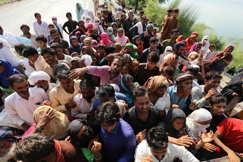 Displaced people wait to receive food aid in the flood-hit Dera Ghazi Khan district of Punjab province. AFP
