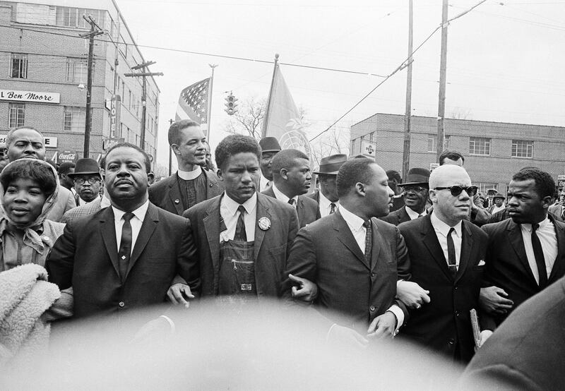 Dr. Martin Luther King Jr., fourth from left, foreground, locks arms with his aides as he leads a march of several thousands to the courthouse in Montgomery, Alabama. From left are: an unidentified woman, Rev. Ralph Abernathy, James Foreman, King, Jesse Douglas Sr., and John Lewis. AP Photo