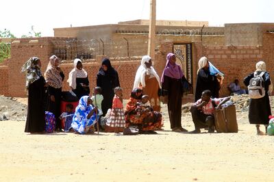 People fleeing street battles wait with their belongings on a road in Khartoum. AFP 