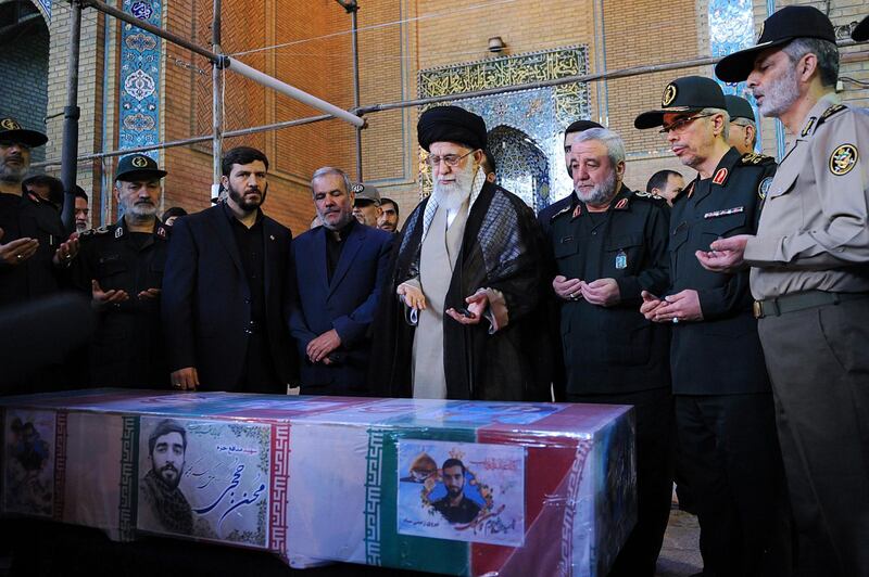 FILE - In this Sept. 27, 2017 file photo released by an official website of the office of the Iranian supreme leader, Supreme Leader Ayatollah Ali Khamenei, center, and military commanders, pray over the coffin of Mohsen Hojaji, a young Revolutionary Guard soldier beheaded by the Islamic State group in Syria, during his state funeral in Tehran, Iran. The protests that broke out in late Dec. 2017 across Iran predominantly involve economic issues, but demonstrators also say the government is sending its young men to fight and die in Syria and spending billions of dollars on the military when it should be focused on providing jobs in Iran and controlling the rising cost of living. (Office of the Iranian Supreme Leader via AP, File)