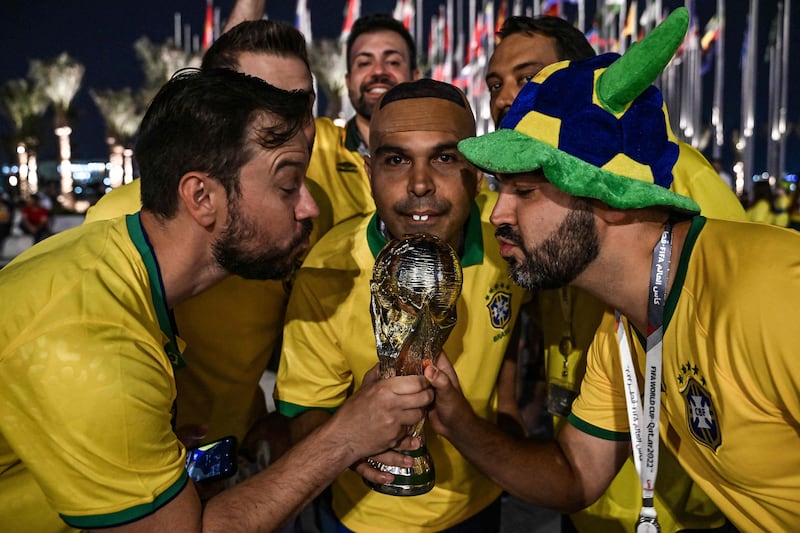 Brazil fans — including a lookalike of Brazilian legend Ronaldo — pose with a replica of the World Cup trophy at Flag Plaza in Doha. AFP