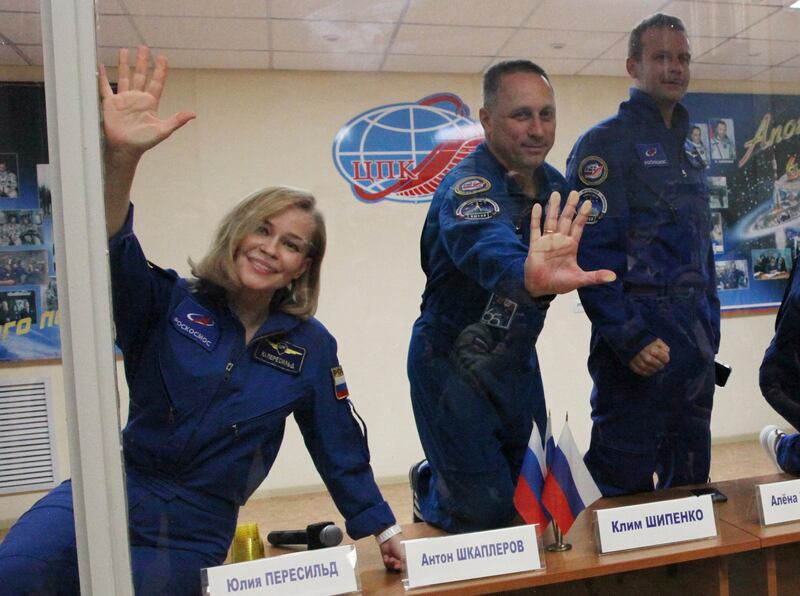 Cosmonaut Anton Shkaplerov (centre), actress Yulia Peresild and film director Klim Shipenko, gesture behind a glass wall during a news conference ahead of the expedition to the International Space Station (ISS). AFP