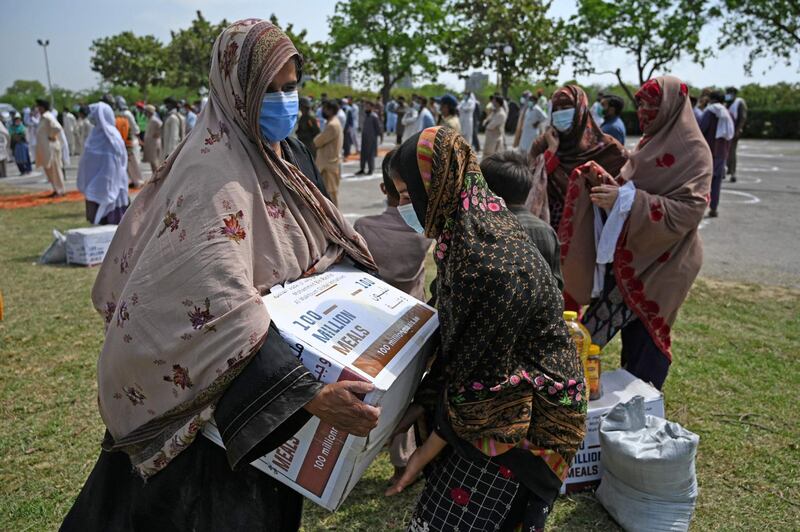 Women carry off boxes of provisions labelled 100 million meals, distributed by the UAE embassy ahead of Ramadan in Islamabad.